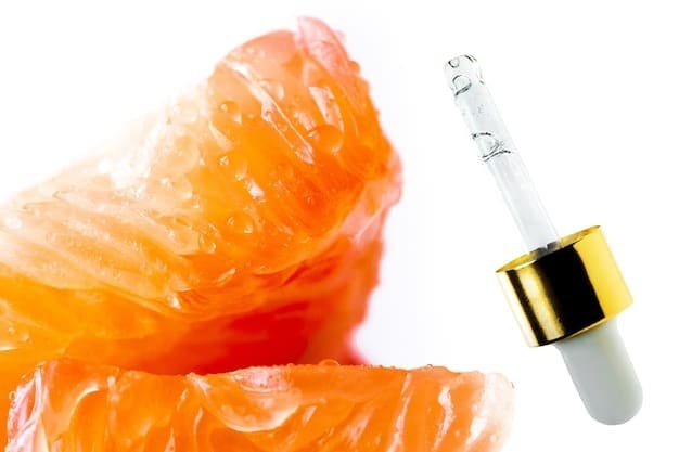 A close-up shot of different skincare products containing Vitamin C, highlighting the ingredient list and the textures of the serums and creams.