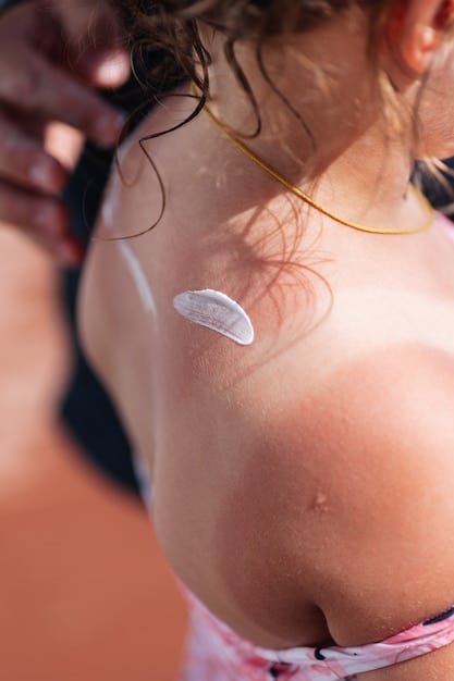 Close-up shot of sunscreen being applied to a person's arm under the sun. The focus is on the texture of the sunscreen, the skin's surface, and the sun's rays.