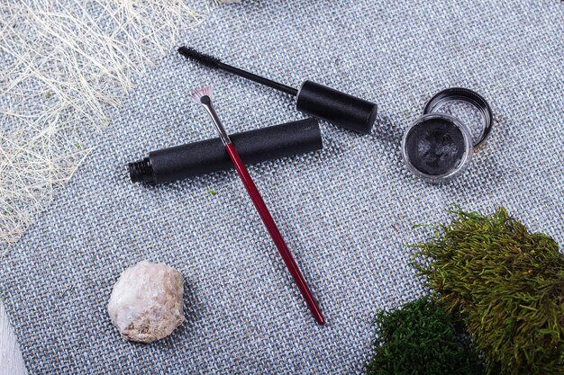 A variety of eyeliner tools, including liquid liner pens, gel liners with angled brushes, and pencil eyeliners, arranged neatly on a makeup table with a blurred background of other cosmetic products.