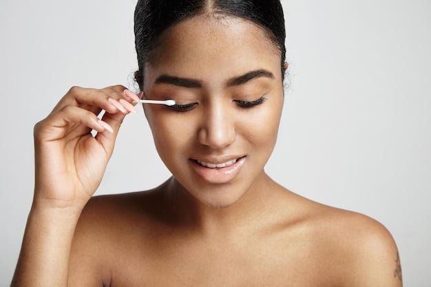 A person using a cotton swab dipped in makeup remover to carefully clean up the edge of a cat-eye, ensuring a sharp and precise line. The focus is on the precision of the cleanup process.